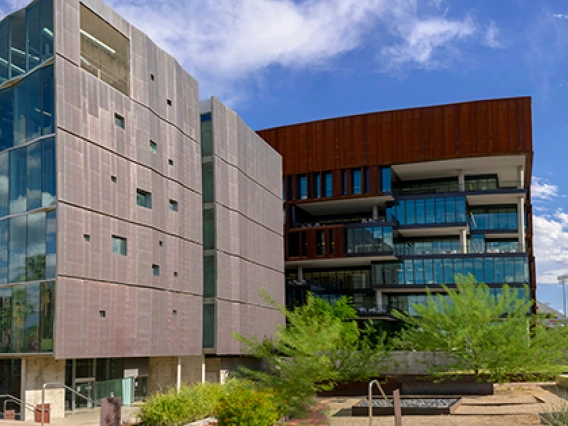 A wide angle photo of the Grand Challenges Research Building taken mid-afternoon in front of a bright blue sky with scattered clouds