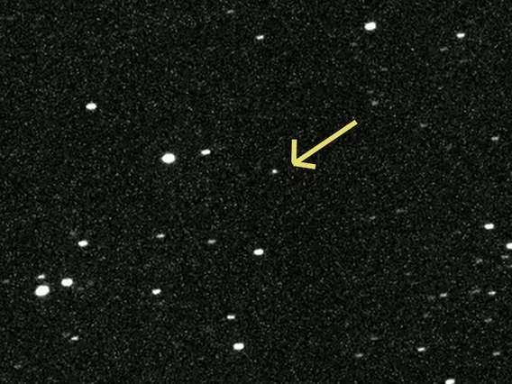 An arrow points to a dot of light among a field of background stars