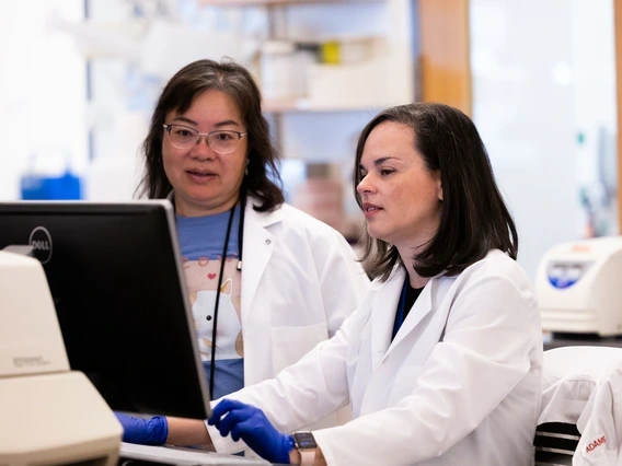 Zelieann Craig looking at a computer monitor in a lab while wearing a lab coat