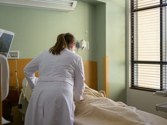 a physician in a white coat caring for a patient in a hospital bed