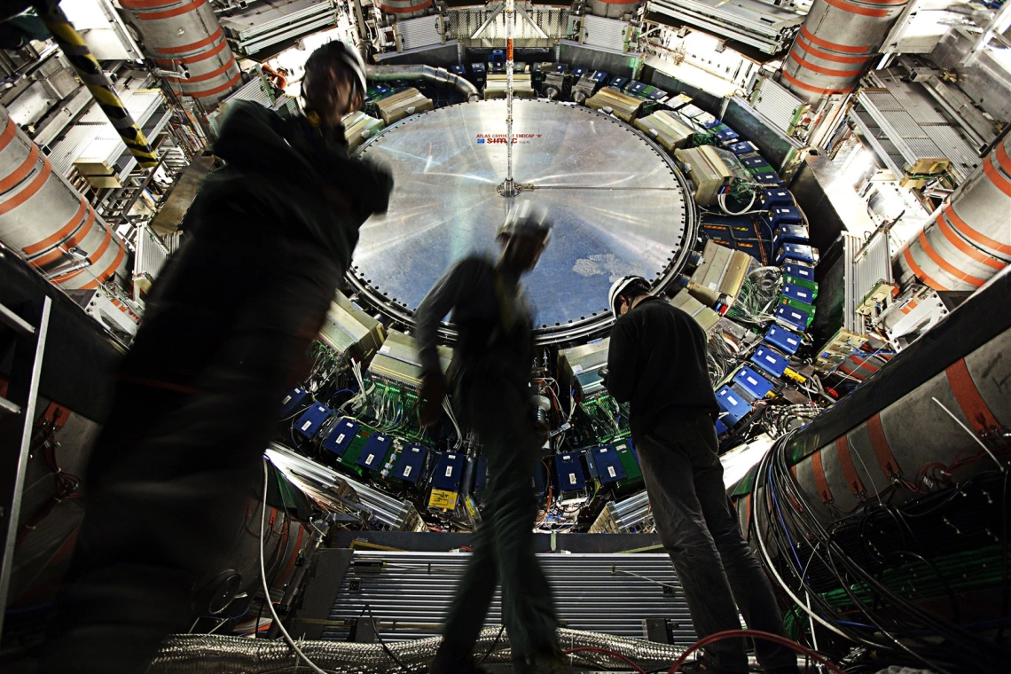 Three individuals stand in front of a large piece of scientific equipment.